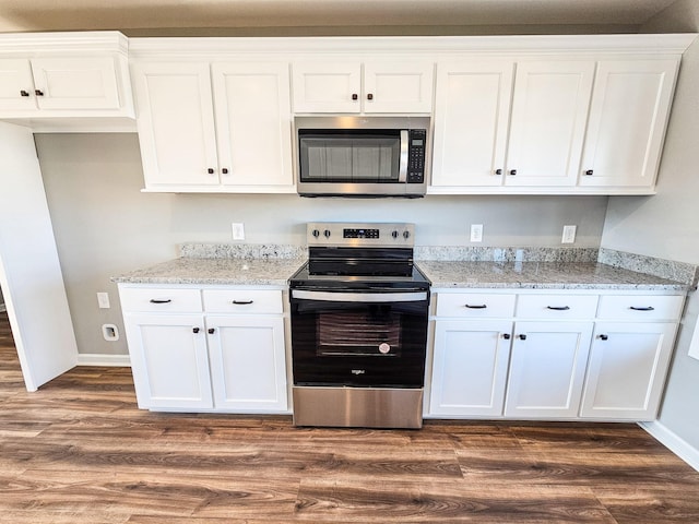 kitchen featuring dark hardwood / wood-style flooring, appliances with stainless steel finishes, white cabinets, and light stone counters