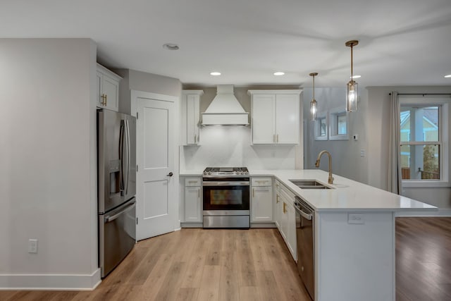 kitchen featuring a peninsula, a sink, light wood-style floors, appliances with stainless steel finishes, and custom range hood