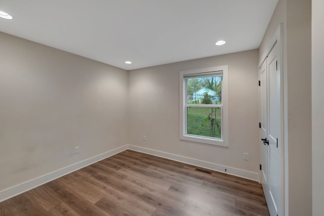 empty room featuring recessed lighting, wood finished floors, visible vents, and baseboards