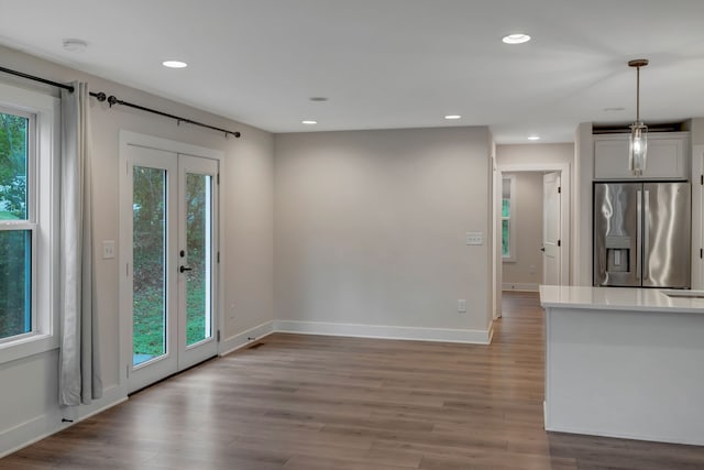 interior space with a healthy amount of sunlight, light wood-style flooring, stainless steel refrigerator with ice dispenser, and french doors