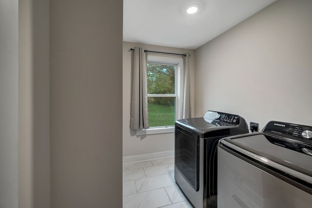 clothes washing area featuring washer and dryer, laundry area, marble finish floor, and baseboards