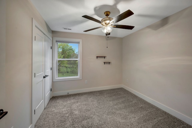 spare room featuring carpet floors, visible vents, ceiling fan, and baseboards