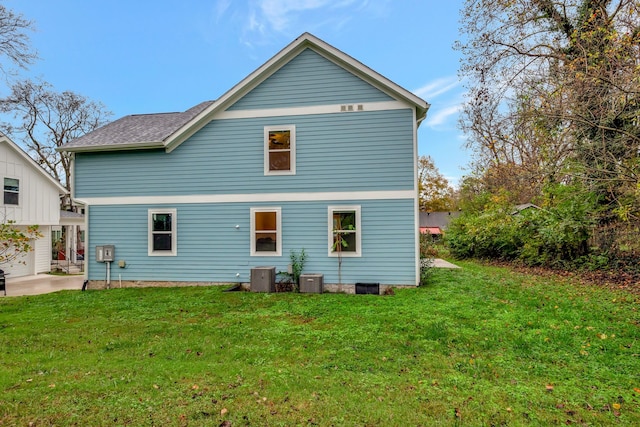 rear view of property featuring a lawn and central AC unit