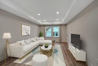 living area with baseboards, a tray ceiling, wood finished floors, and recessed lighting