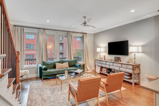 living room with ceiling fan, light wood-type flooring, and ornamental molding