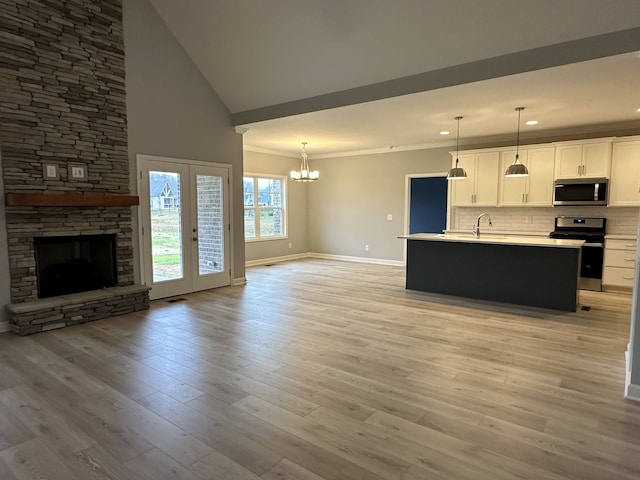 kitchen featuring white cabinets, stainless steel appliances, hanging light fixtures, and an island with sink