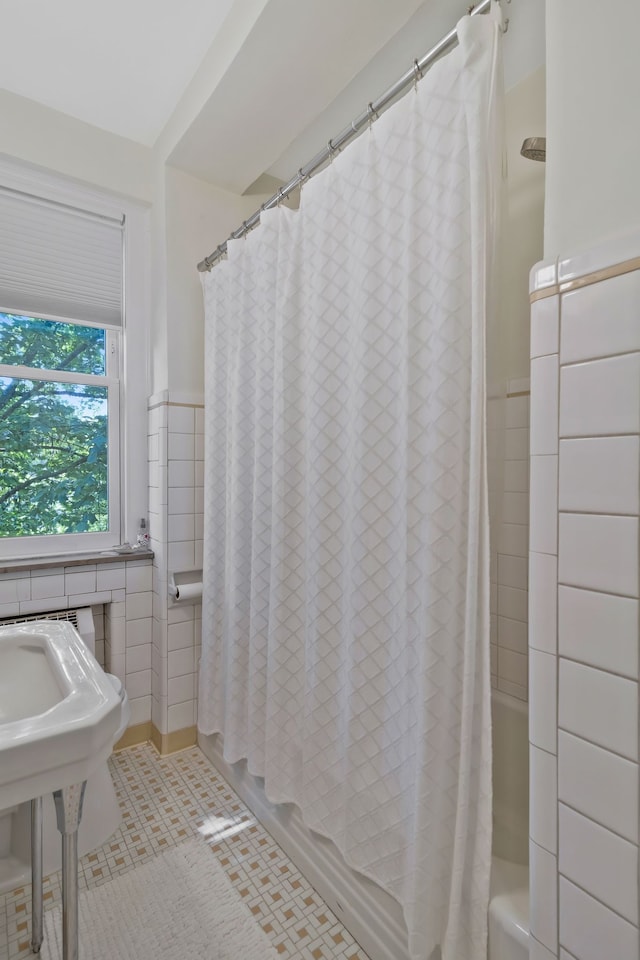 bathroom with tile patterned floors, shower / tub combo with curtain, and tile walls