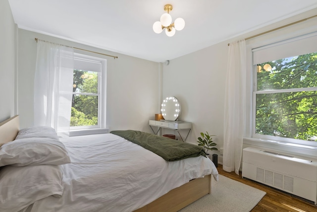 bedroom featuring radiator heating unit, dark wood-type flooring, and a notable chandelier