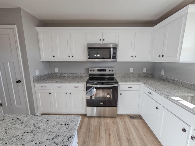 kitchen featuring white cabinetry, stainless steel appliances, and light wood-type flooring