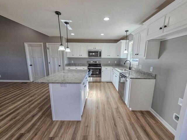 kitchen with a kitchen island, appliances with stainless steel finishes, decorative light fixtures, sink, and white cabinets