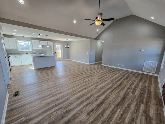 unfurnished living room with hardwood / wood-style flooring, ceiling fan, sink, and vaulted ceiling