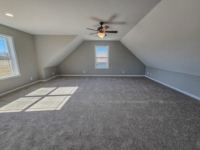 additional living space with dark colored carpet, lofted ceiling, and ceiling fan