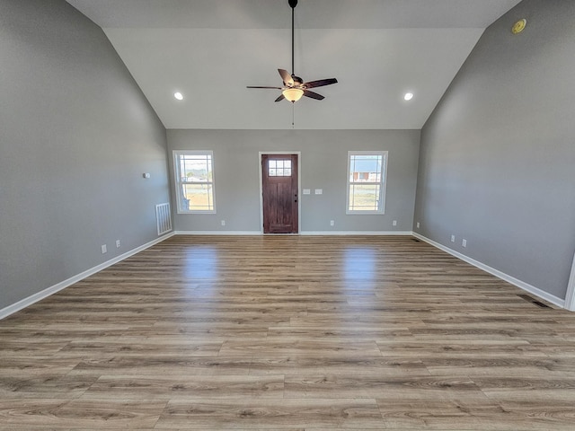 unfurnished living room featuring ceiling fan, plenty of natural light, high vaulted ceiling, and light wood-type flooring