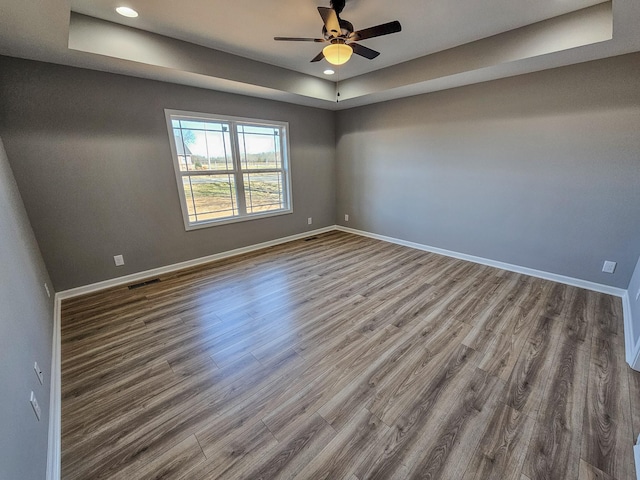 spare room featuring a tray ceiling, wood-type flooring, and ceiling fan