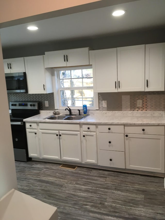 kitchen with sink, white cabinetry, backsplash, stainless steel appliances, and dark hardwood / wood-style flooring