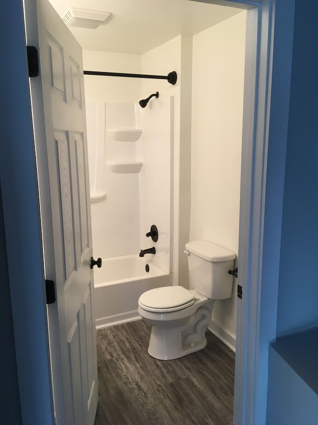 bathroom featuring hardwood / wood-style flooring, shower / washtub combination, and toilet