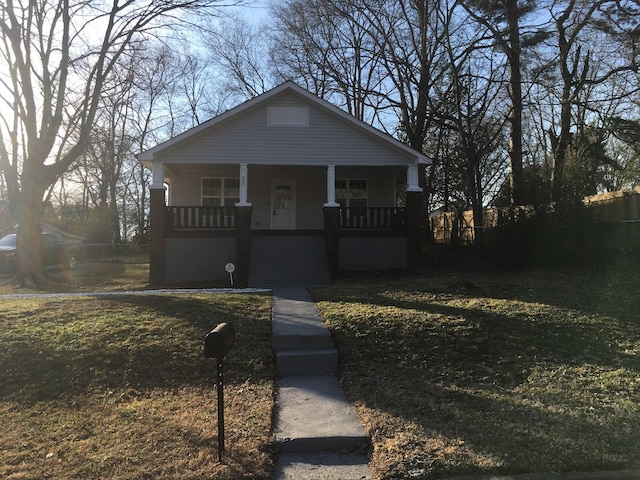 bungalow-style home with a front yard and covered porch