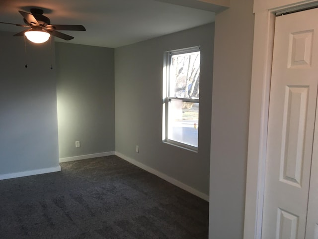 unfurnished room featuring ceiling fan and dark colored carpet