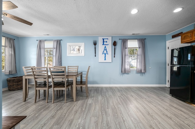 dining space with ceiling fan, light hardwood / wood-style floors, and a textured ceiling