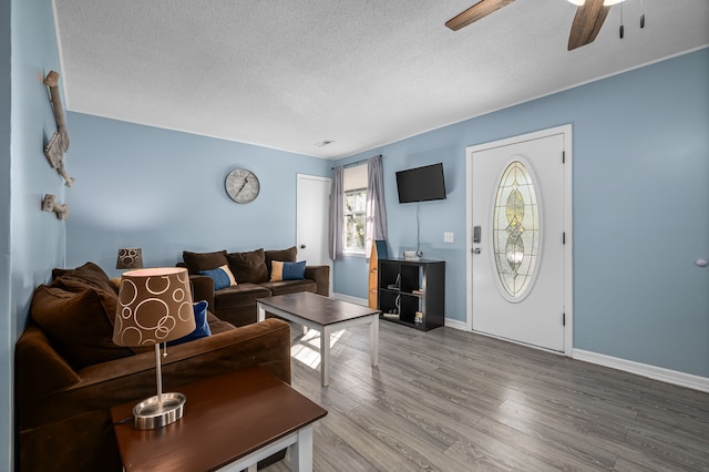 living room with hardwood / wood-style floors, ceiling fan, and a textured ceiling