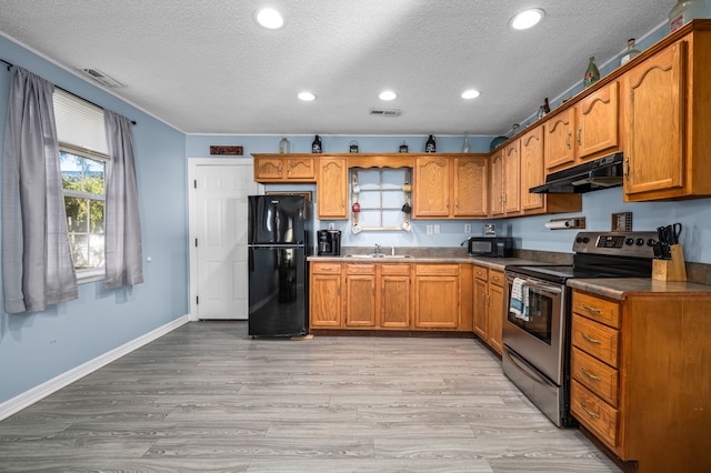 kitchen with black appliances, sink, light wood-type flooring, and a textured ceiling