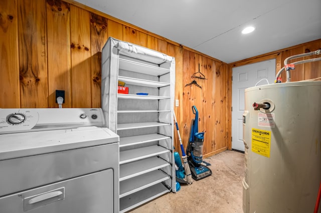 washroom featuring electric water heater, wood walls, and washer / dryer