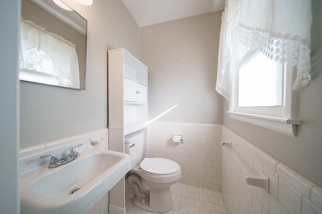 bathroom with tile patterned floors, toilet, tile walls, and sink