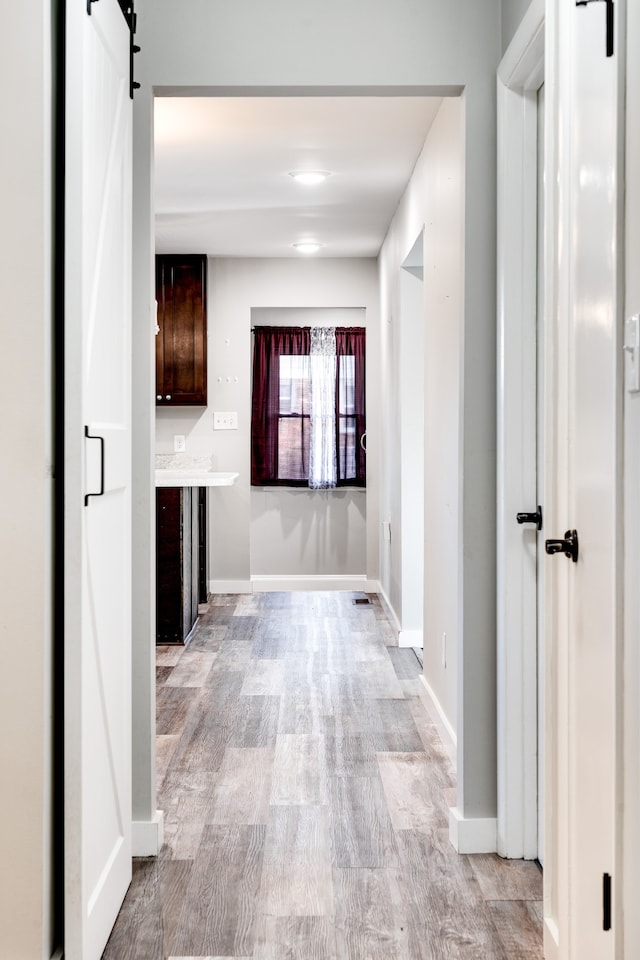 hall with a barn door and light hardwood / wood-style flooring