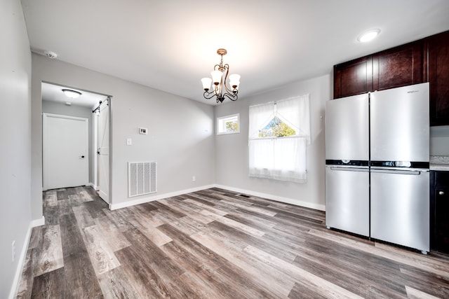 unfurnished dining area with light hardwood / wood-style floors and an inviting chandelier