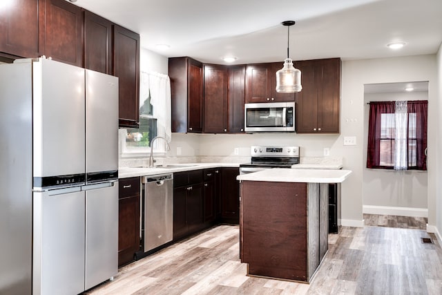 kitchen featuring sink, hanging light fixtures, light wood-type flooring, a kitchen island, and stainless steel appliances