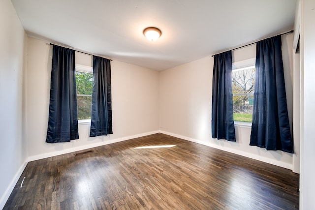 empty room with dark hardwood / wood-style floors and a healthy amount of sunlight