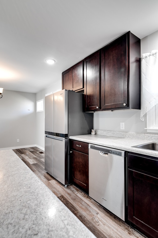 kitchen featuring appliances with stainless steel finishes, dark brown cabinetry, and light hardwood / wood-style floors