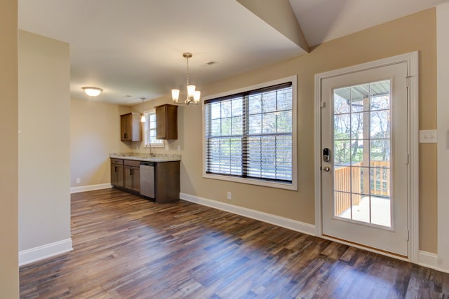 kitchen featuring pendant lighting, an inviting chandelier, vaulted ceiling, stainless steel dishwasher, and dark hardwood / wood-style flooring