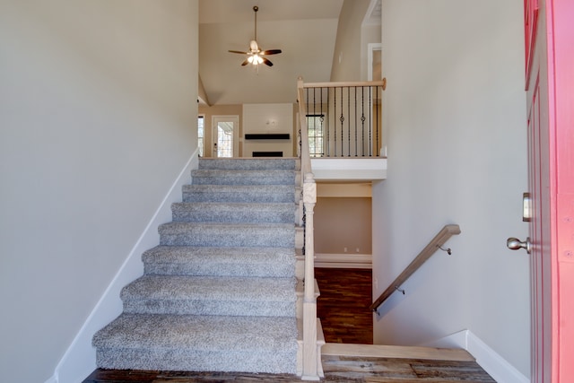 staircase featuring ceiling fan, high vaulted ceiling, and hardwood / wood-style flooring