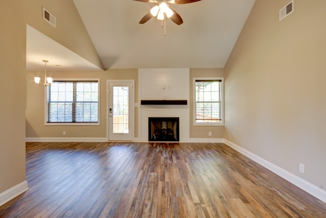 unfurnished living room with ceiling fan with notable chandelier, hardwood / wood-style flooring, and lofted ceiling