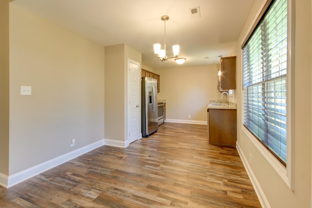 kitchen with stainless steel fridge with ice dispenser, pendant lighting, wood-type flooring, and a notable chandelier