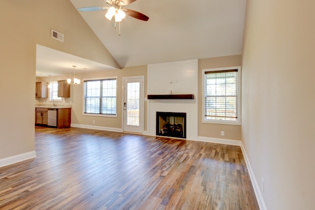 unfurnished living room featuring sink, high vaulted ceiling, wood-type flooring, and ceiling fan with notable chandelier