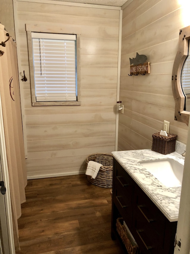 bathroom with vanity, hardwood / wood-style flooring, and wooden walls