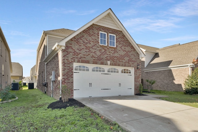 view of side of property with a lawn, a garage, and central AC