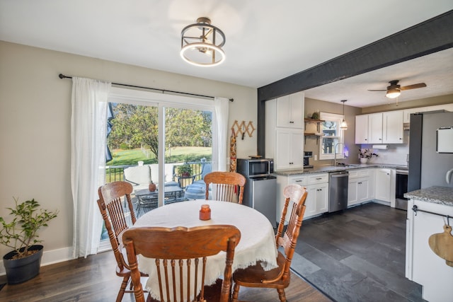 dining area with beamed ceiling, ceiling fan with notable chandelier, sink, and dark wood-type flooring