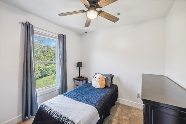 carpeted bedroom featuring multiple windows and ceiling fan