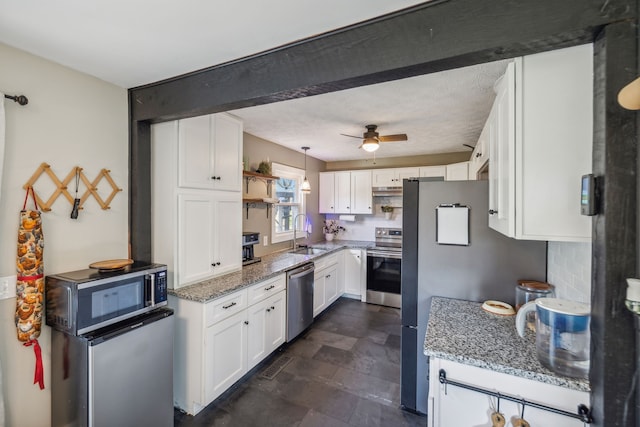 kitchen featuring stone counters, white cabinetry, sink, decorative light fixtures, and appliances with stainless steel finishes