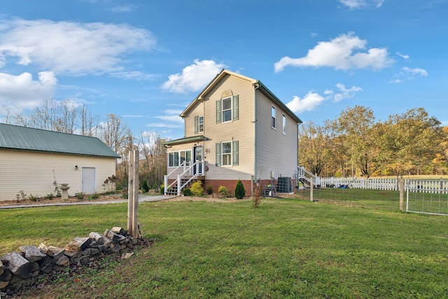 rear view of property featuring a lawn and central air condition unit