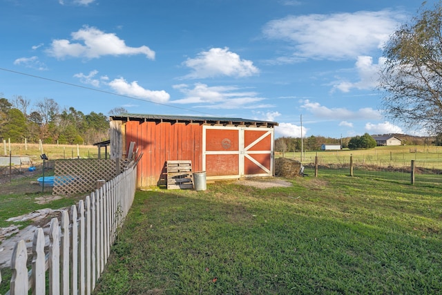 view of outbuilding with a rural view and a lawn