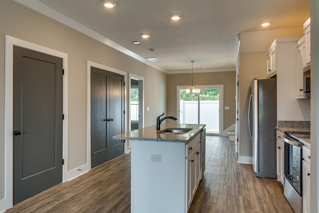 kitchen featuring hardwood / wood-style floors, an island with sink, appliances with stainless steel finishes, decorative light fixtures, and white cabinetry