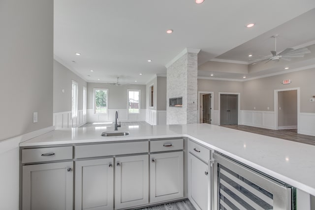 kitchen featuring kitchen peninsula, sink, wine cooler, and ornamental molding