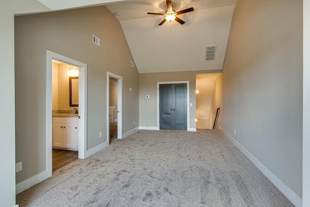 unfurnished bedroom featuring ensuite bath, ceiling fan, high vaulted ceiling, and light colored carpet