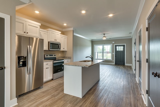 kitchen with white cabinets, sink, stainless steel appliances, and an island with sink