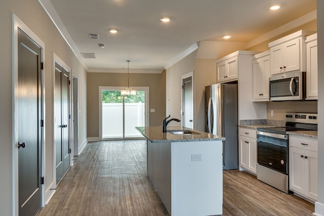 kitchen featuring pendant lighting, wood-type flooring, a center island with sink, white cabinets, and appliances with stainless steel finishes