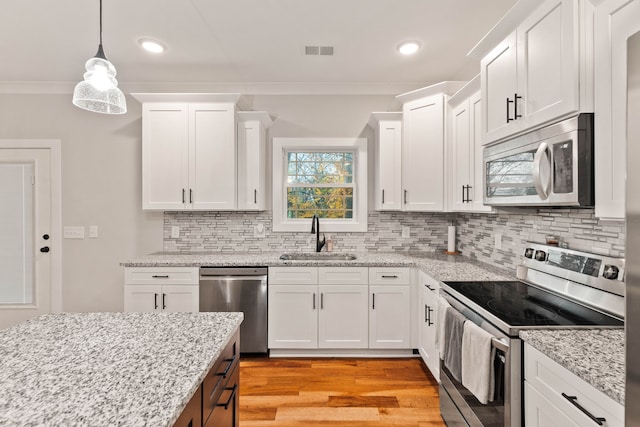 kitchen featuring appliances with stainless steel finishes, backsplash, sink, white cabinets, and light hardwood / wood-style floors